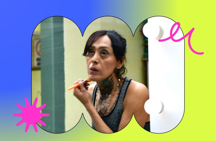 Una mujer trans se maquilla frente al espejo.